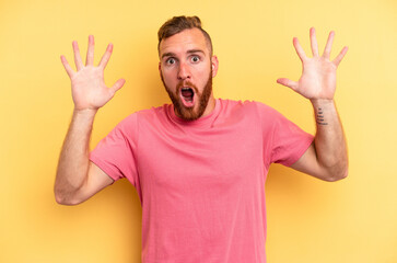 Naklejka premium Young caucasian man isolated on yellow background celebrating a victory or success, he is surprised and shocked.
