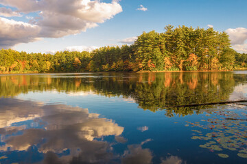 Colorful fall foliage with dramatic clouds and reflection in water.