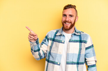 Fototapeta premium Young caucasian man isolated on yellow background smiling cheerfully pointing with forefinger away.