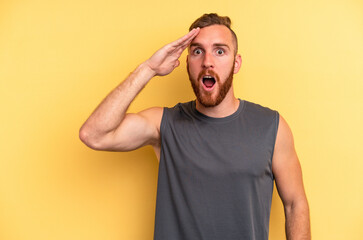 Young caucasian man isolated on yellow background shouts loud, keeps eyes opened and hands tense.