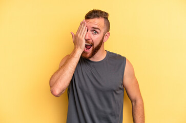 Young caucasian man isolated on yellow background having fun covering half of face with palm.