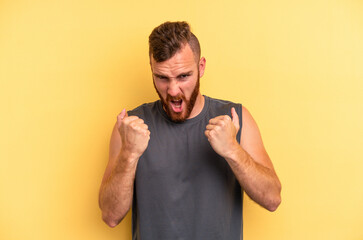 Young caucasian man isolated on yellow background upset screaming with tense hands.