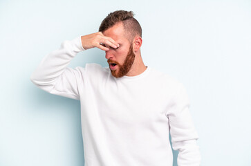 Young caucasian man isolated on blue background having a head ache, touching front of the face.