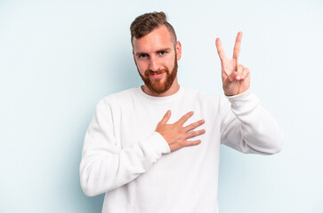 Young caucasian man isolated on blue background taking an oath, putting hand on chest.