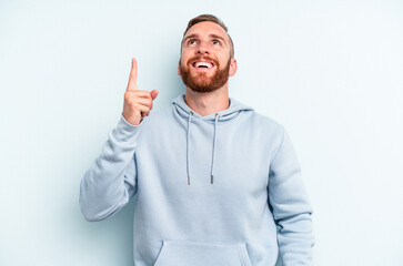 Fototapeta premium Young caucasian man isolated on blue background indicates with both fore fingers up showing a blank space.