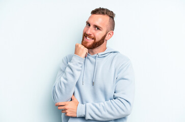 Young caucasian man isolated on blue background smiling happy and confident, touching chin with hand.