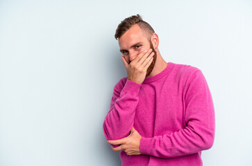 Young caucasian man isolated on blue background laughing happy, carefree, natural emotion.