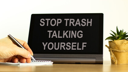 Stop trash talking yourself symbol. Concept words Stop trash talking yourself on the black tablet. Businessman hand with pen. Psychological stop trash talking yourself concept. Copy space.