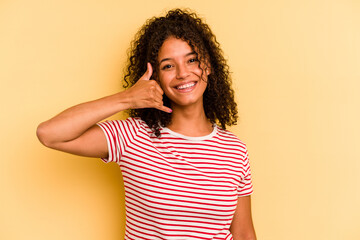 Young Brazilian woman isolated on yellow background showing a mobile phone call gesture with fingers.