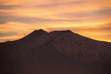 Panoramic view on silhouette of hills during twilight. Watching beautiful sunset behind volcano Mount Etna near Castelmola, Taormina, Sicily, Italy, Europe, EU. Clouds with vibrant red orange colors