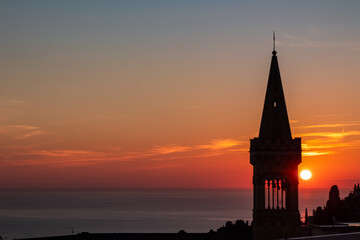 Fototapeta premium Watching beautiful sunrise at the Mediterranean sea in Taormina, Sicily, Italy, Europe, EU. Silhouette of tower of church Chiesa di Sant Antonio da Padova in the foreground. Vibrant red orange colors