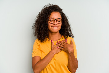 Young Brazilian woman isolated on blue background has friendly expression, pressing palm to chest....