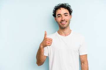Young caucasian man isolated on blue background smiling and raising thumb up