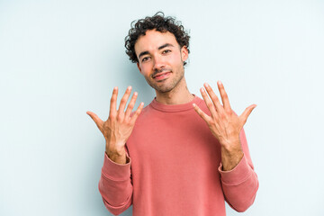 Fototapeta premium Young caucasian man isolated on blue background showing number ten with hands.