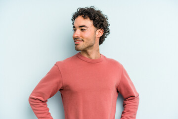 Young caucasian man isolated on blue background confident keeping hands on hips.