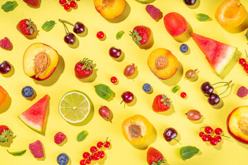 Summer vitamin food concept, various fruit and berries watermelon peach mint plum apricots blueberry strawberry currant, creative flat lay on yellow background top view copy space
