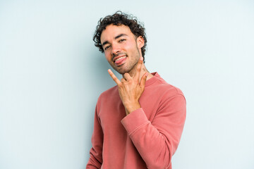 Fototapeta na wymiar Young caucasian man isolated on blue background showing rock gesture with fingers