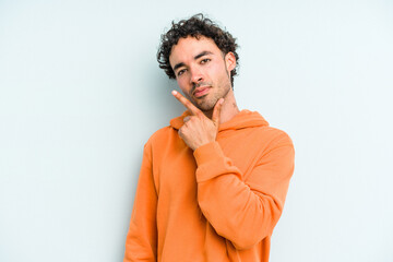 Fototapeta premium Young caucasian man isolated on blue background contemplating, planning a strategy, thinking about the way of a business.