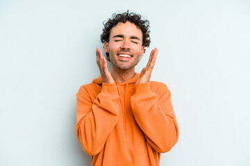 Young caucasian man isolated on blue background laughs out loudly keeping hand on chest.
