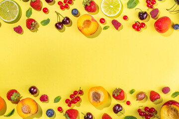 Summer vitamin food concept, various fruit and berries watermelon peach mint plum apricots blueberry strawberry currant, creative flat lay on yellow background top view copy space