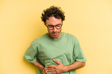 Young caucasian man isolated on yellow background having a liver pain, stomach ache.