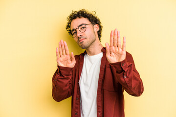 Young caucasian man isolated on yellow background standing with outstretched hand showing stop...