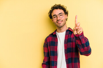 Naklejka premium Young caucasian man isolated on yellow background showing number one with finger.