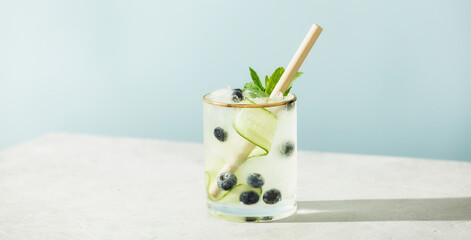 Trendy summer drinks with cucumber, mint and blueberry on blue sky background