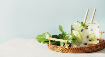 Trendy and healthy summer infused vitamin water with cucumber, mint and blueberry in wicker tray on...