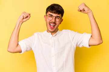 Young caucasian man isolated on yellow background showing strength gesture with arms, symbol of feminine power