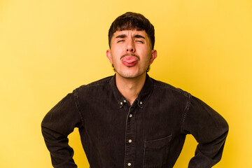 Young caucasian man isolated on yellow background funny and friendly sticking out tongue.