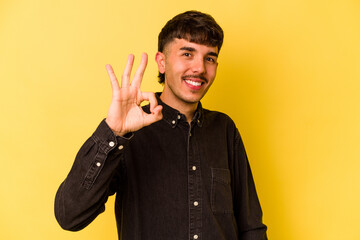 Young caucasian man isolated on yellow background cheerful and confident showing ok gesture.