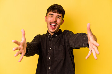 Young caucasian man isolated on yellow background feels confident giving a hug to the camera.