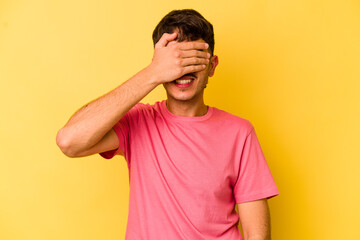 Obraz premium Young caucasian man isolated on yellow background covers eyes with hands, smiles broadly waiting for a surprise.