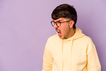 Young caucasian man isolated on purple background shouting very angry, rage concept, frustrated.