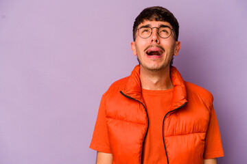 Young caucasian man isolated on purple background shouting very angry, rage concept, frustrated.