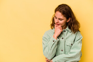 Young caucasian woman isolated on yellow background looking sideways with doubtful and skeptical expression.