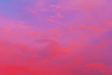 Clouds illuminated by the setting sun. Red sunset in the evening sky. Colorful dramatic view with red and purple clouds.