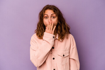 Young caucasian woman isolated on purple background shocked, covering mouth with hands, anxious to discover something new.