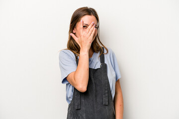 Young caucasian pregnant woman isolated on white background blink at the camera through fingers, embarrassed covering face.