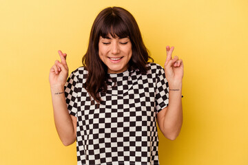 Young caucasian woman isolated on yellow background crossing fingers for having luck