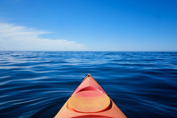 View of the bow of a kayak towards the immense blue sea
