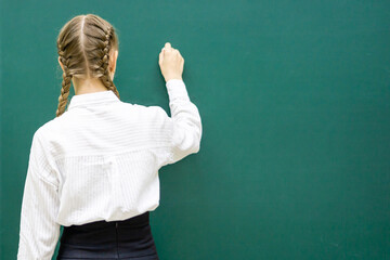 A photo of a smart student about to write something on the blackboard. Space for text. The concept...