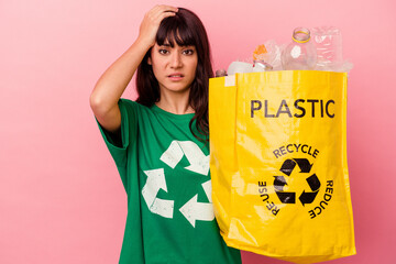 Young caucasian woman holding a recycled plastic bag isolated on pink background being shocked, she has remembered important meeting.