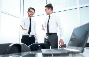 Two businessmen shaking hands standing at big window