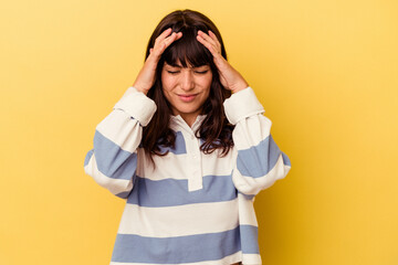 Young caucasian woman isolated on yellow background having a head ache, touching front of the face.