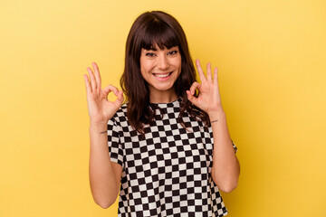 Young caucasian woman isolated on yellow background cheerful and confident showing ok gesture.