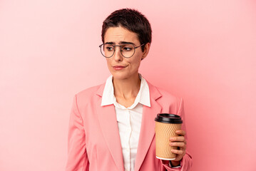 Young caucasian business woman holding a takeaway coffee isolated on pink background confused, feels doubtful and unsure.