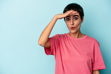 Young caucasian woman isolated on blue background looking far away keeping hand on forehead.