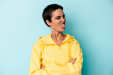 Young caucasian woman isolated on blue background funny and friendly sticking out tongue.